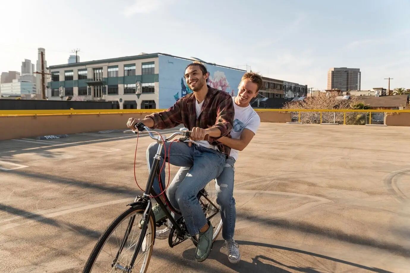 Full-body shot of happy men riding a bicycle