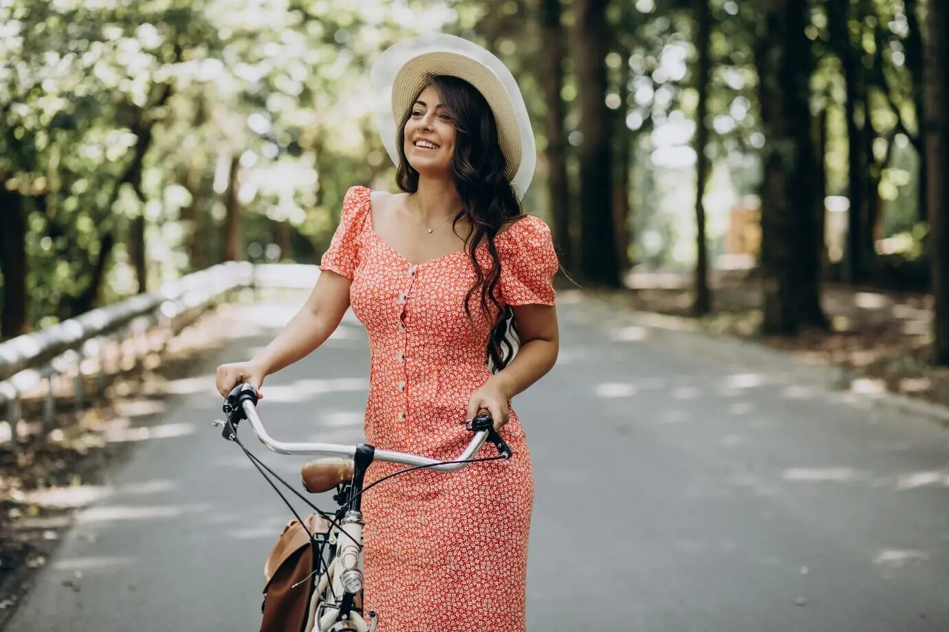 A young, attractive woman wearing a dress rides a bicycle.