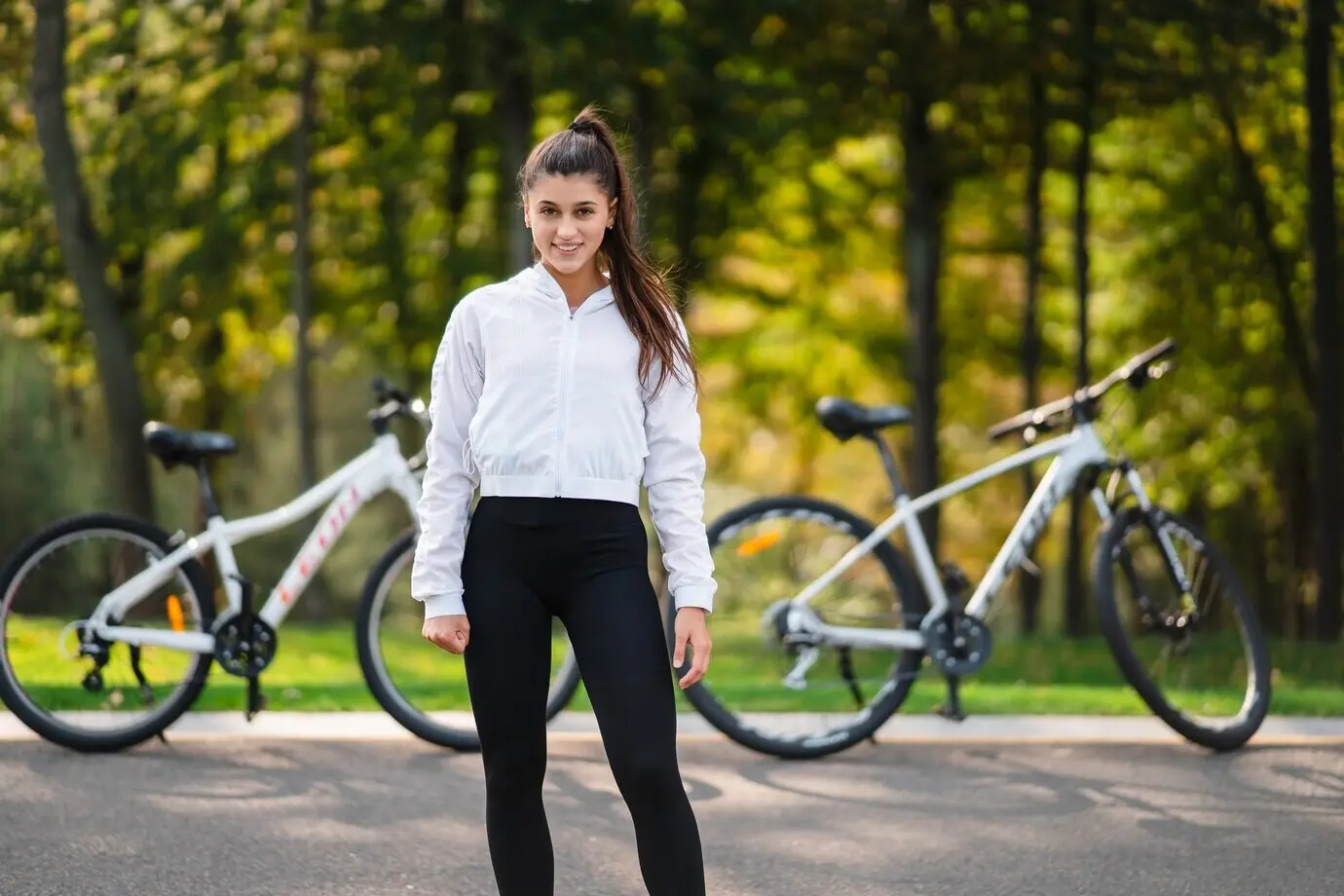 A beautiful girl poses with a white bicycle during a walk in nature.