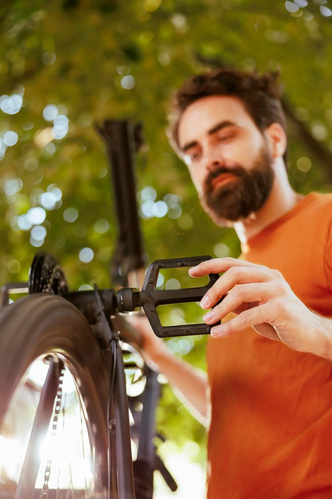 A man fixes a bicycle pedal outside.