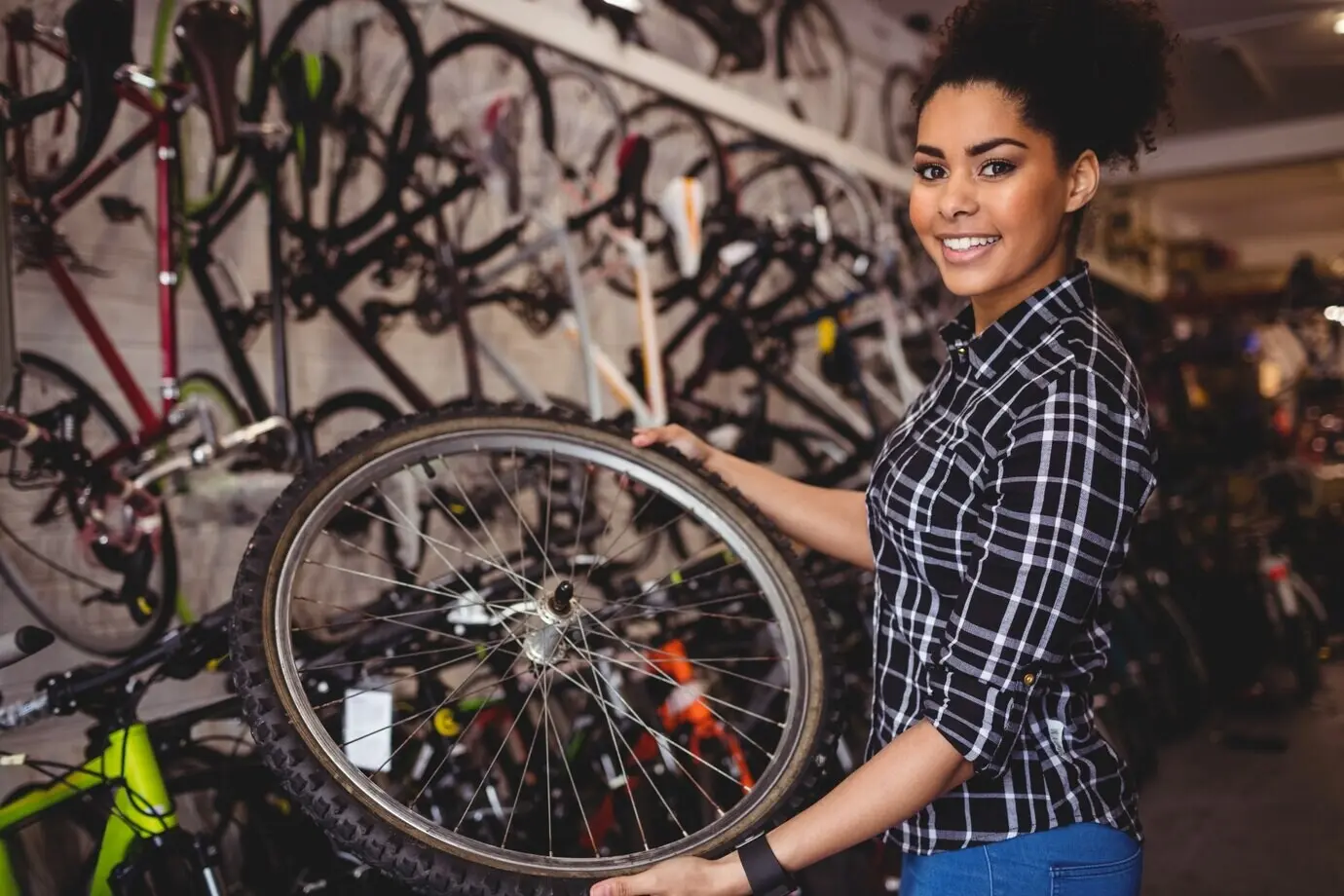 A mechanic is holding a bicycle wheel.